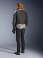 Giacca impermeabile Alpinestars T-Jaws V4, vista posteriore, Black Ice Gray e Dark Gray, con logo Alpinestars giallo neon sulla parte bassa della schiena, indossata con pantaloni neri e guanti da moto, abbigliamento da guida sportivo