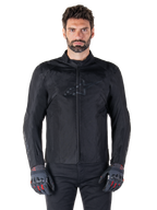 Giacca Alpinestars T-SPS V2 Waterproof, giacca da moto in tessuto nero, indossata da un pilota con guanti neri e rossi, dotata di colletto alto, zip frontale e logo discreto sul petto, protezione impermeabile per guida sportiva e urbana