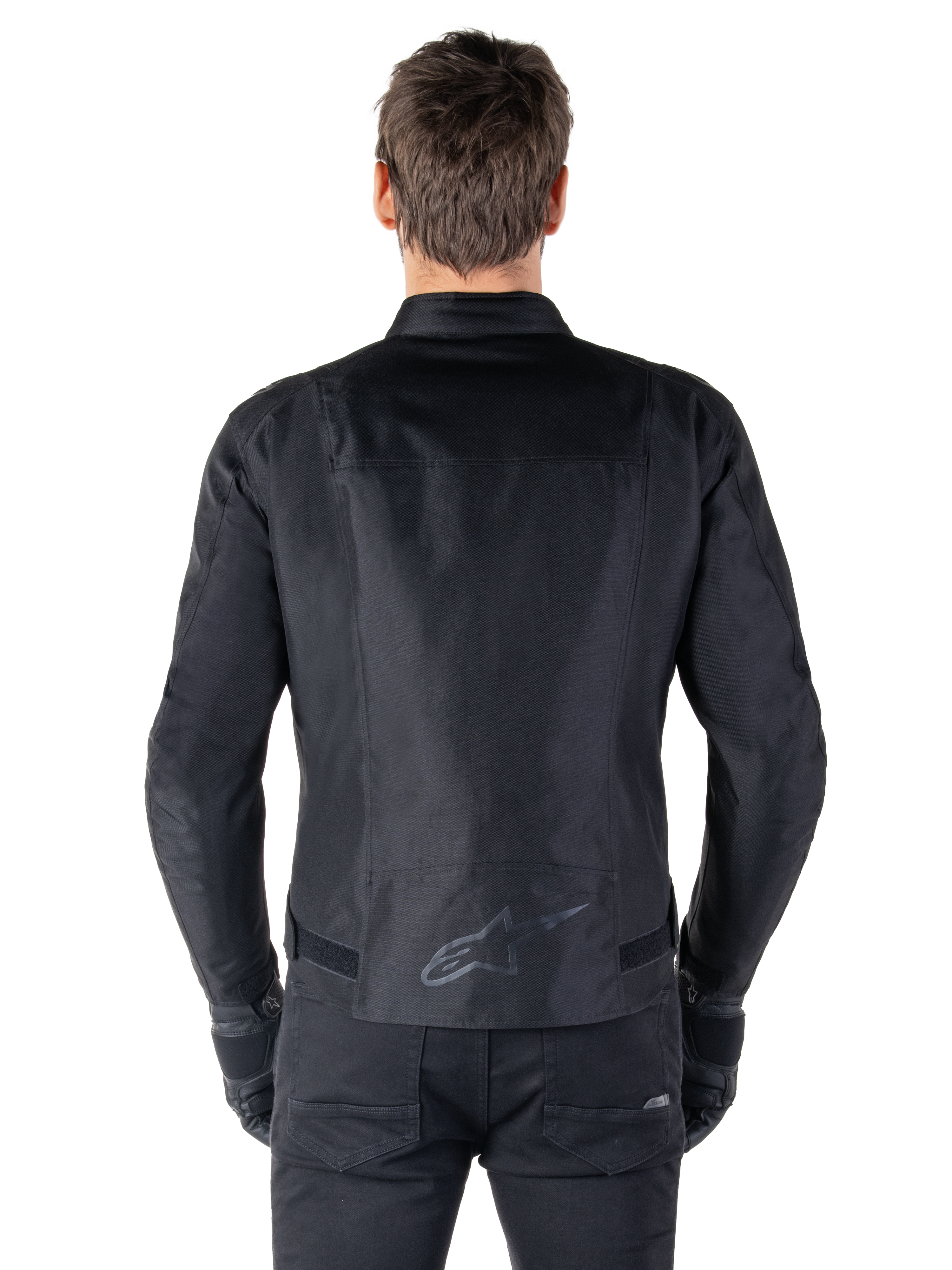 Giacca Alpinestars T-SPS V2 Waterproof, nero, vista posteriore con silhouette dal taglio sportivo, logo Alpinestars riflettente sulla parte bassa della schiena e parte posteriore allungata per una maggiore copertura durante la guida.