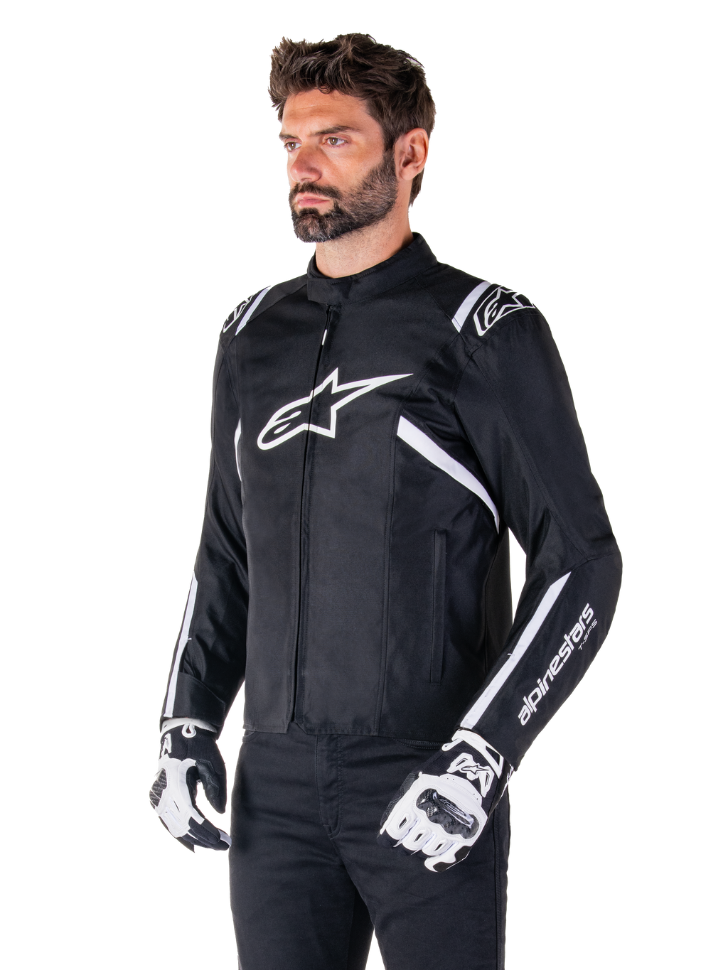 Giacca Alpinestars T-SPS V2 Waterproof, nero e bianco, indossata da un modello con guanti da moto coordinati, giacca in tessuto dal taglio sportivo con loghi Alpinestars bianchi su petto e spalle, marchio 'alpinestars T-SPS' sulla manica, abbigliamento da moto elegante d'ispirazione racing