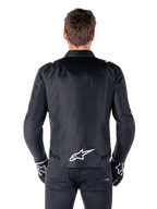Giacca Alpinestars T-SPS V2 Waterproof, nero e bianco, vista posteriore con logo Alpinestars bianco sulla parte bassa della schiena, indossata con pantaloni e guanti neri, giacca da moto in tessuto con taglio sportivo