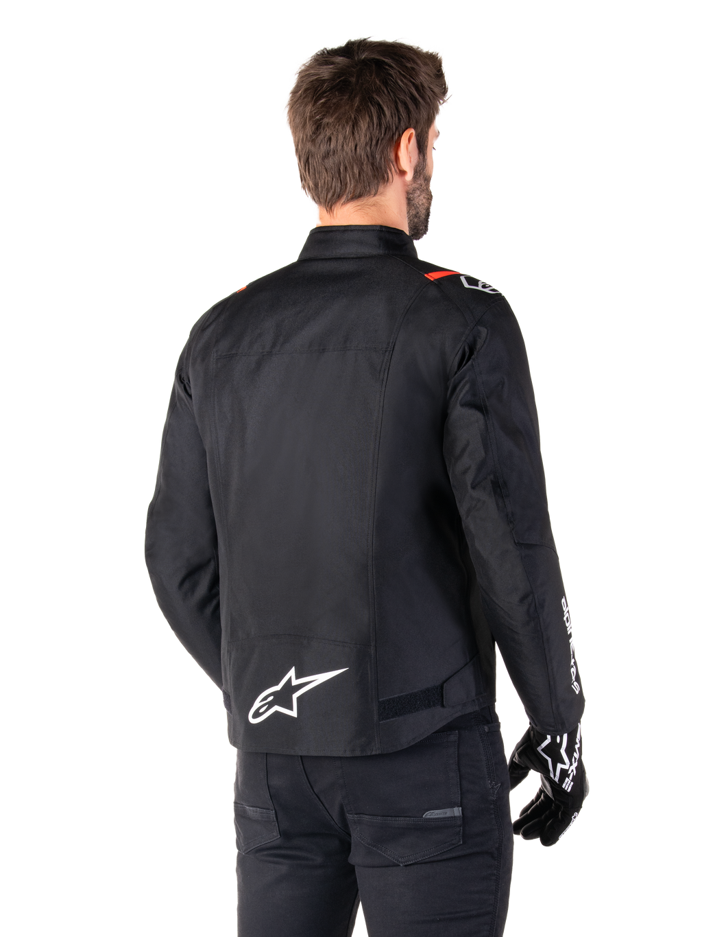 Giacca impermeabile Alpinestars T-SPS V2, nero bianco rosso fluo, vista posteriore, con logo Alpinestars bianco sulla parte bassa della schiena e dettagli rossi sulle spalle, indossata con guanti e pantaloni da moto neri, giacca da moto sportiva in tessuto.