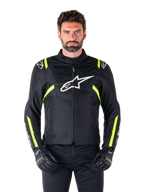 Alpinestars T-SPS V2 Waterproof Jacket, giacca da moto, nero con accenti bianco e giallo fluo, indossata da un modello con guanti neri, con logo a stella bianco sul petto e strisce giallo neon su maniche e spalle, abbigliamento sportivo in tessuto per ogni condizione climatica