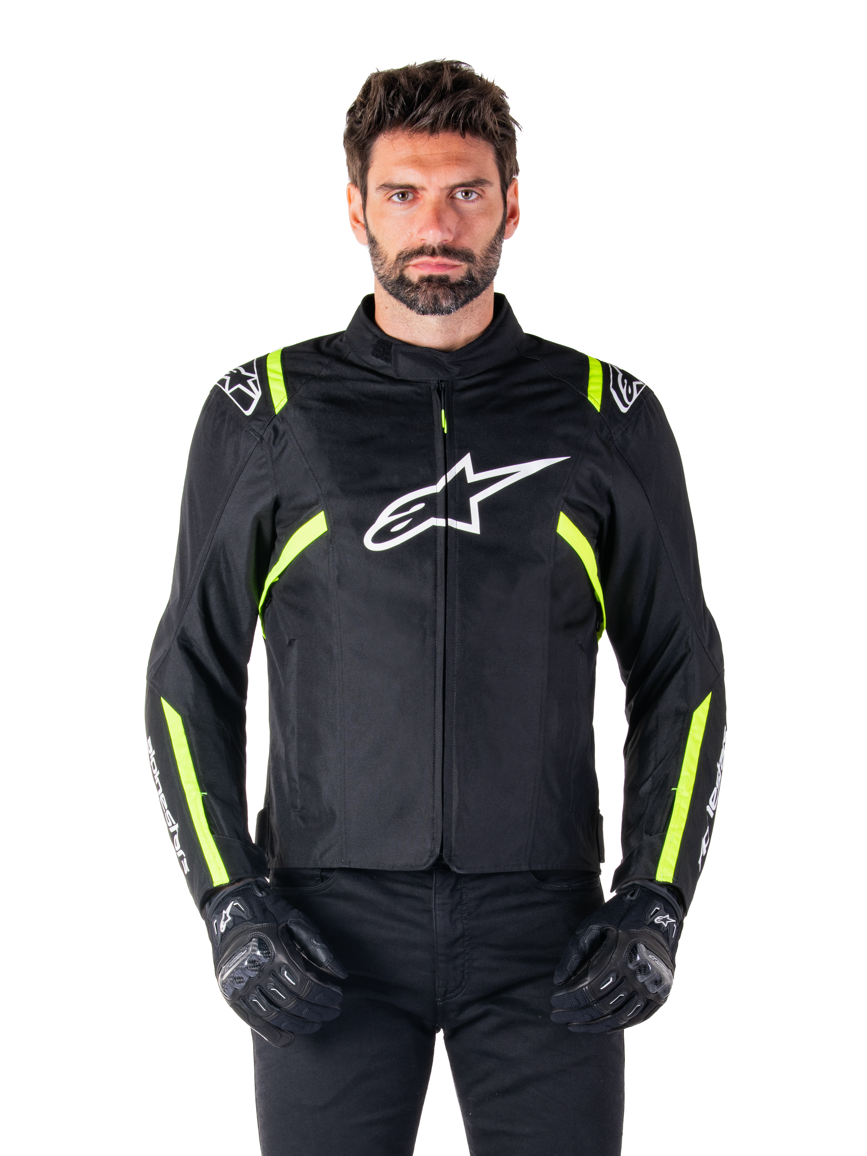 Alpinestars T-SPS V2 Waterproof Jacket, giacca da moto, nero con accenti bianco e giallo fluo, indossata da un modello con guanti neri, con logo a stella bianco sul petto e strisce giallo neon su maniche e spalle, abbigliamento sportivo in tessuto per ogni condizione climatica