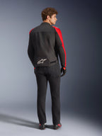 Giacca impermeabile Alpinestars T-SPS V2, nero rosso rosso fluo, vista posteriore su modello, logo Alpinestars bianco sulla parte bassa della schiena, indossata con pantaloni da moto neri e guanti, giacca sportiva da moto in tessuto impermeabile