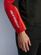 Alpinestars Giacca Impermeabile T-SPS V2, giacca da moto, nero e rosso, primo piano della manica con logo verticale bianco del brand su un pannello rosso, struttura in tessuto resistente con design d'ispirazione sportiva.