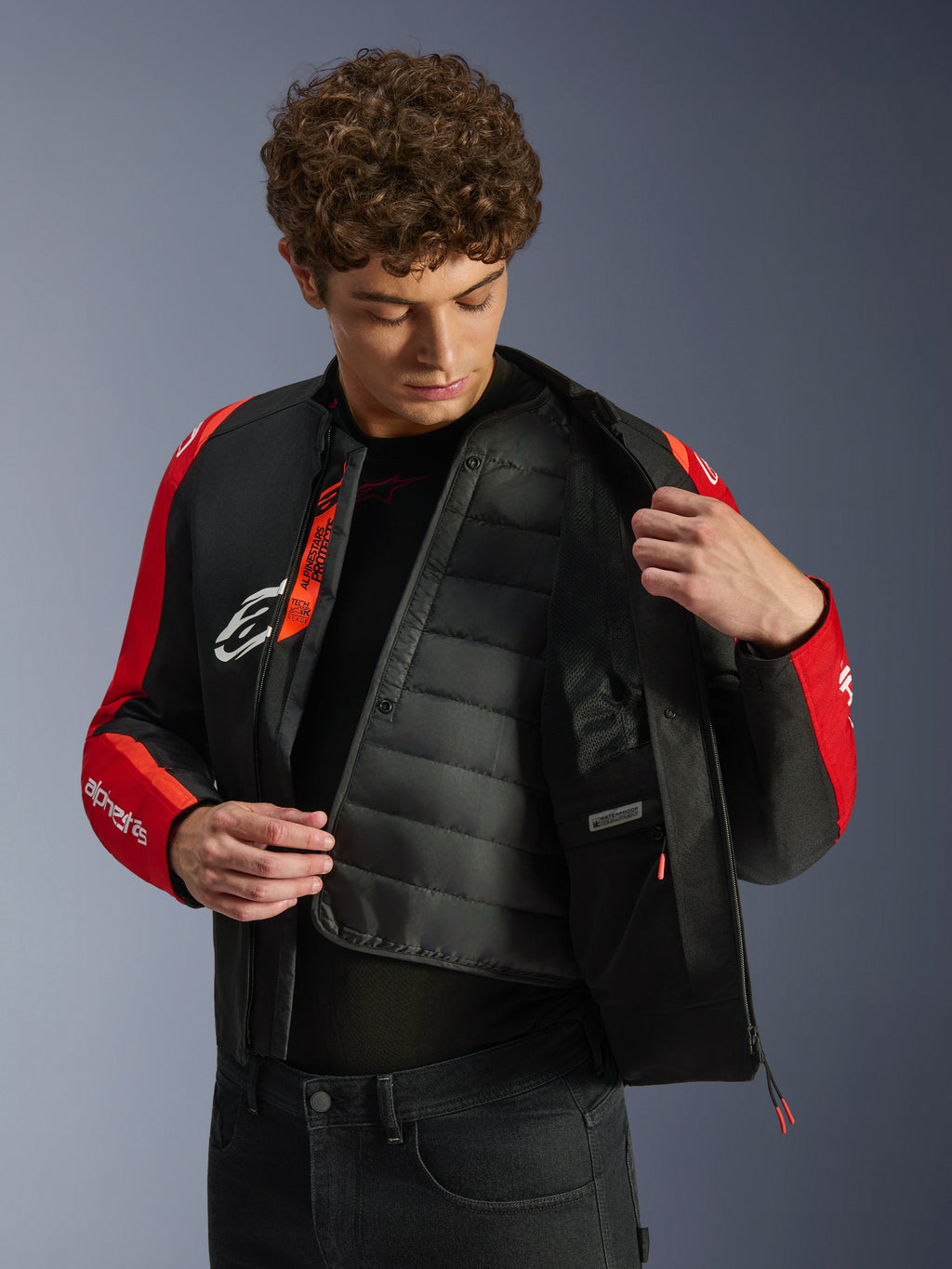 Giacca impermeabile Alpinestars T-SPS V2, nero e rosso, modello che mostra la fodera termica trapuntata interna e lo scomparto impermeabile, logo Tech-Air Ready all'interno, giacca da moto dal taglio sportivo