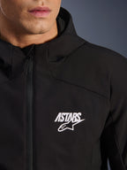 Alpinestars Aeroshell Waterproof Jacket, giacca softshell da moto nera, vista ravvicinata del petto con logo a stella ASTARS bianco e cerniera anteriore impermeabile, cappuccio integrato, design sportivo moderno
