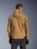 Giacca impermeabile Alpinestars Aeroshell, Dark Khaki e Arancione Fluo, vista posteriore con design a felpa con cappuccio e profili arancioni su cappuccio e orlo, logo arancione sulla parte bassa della schiena, indossata con guanti neri, abbigliamento da moto softshell sportivo crossover.