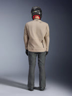 Giacca Alpinestars Borrego Drystar®, giacca da moto adventure Warm Gray, vista posteriore che mostra l'aspetto in tela cerata con pannelli di espansione sulle spalle e tasca posteriore inferiore con zip, indossata con pantaloni da guida grigio scuro e casco nero.