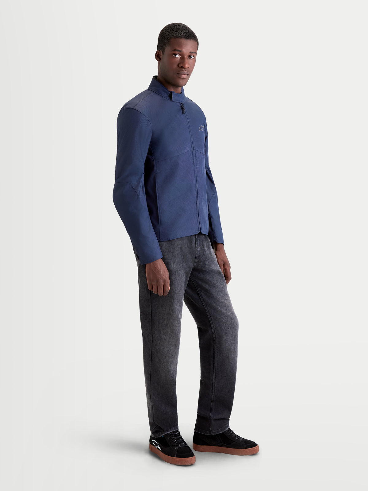 Alpinestars C-1 Waterproof Giacca, giacca da moto in tessuto urban contemporary da uomo in colore blu scuro, vista laterale di profilo su un modello che indossa pantaloni scuri e scarpe da moto casual