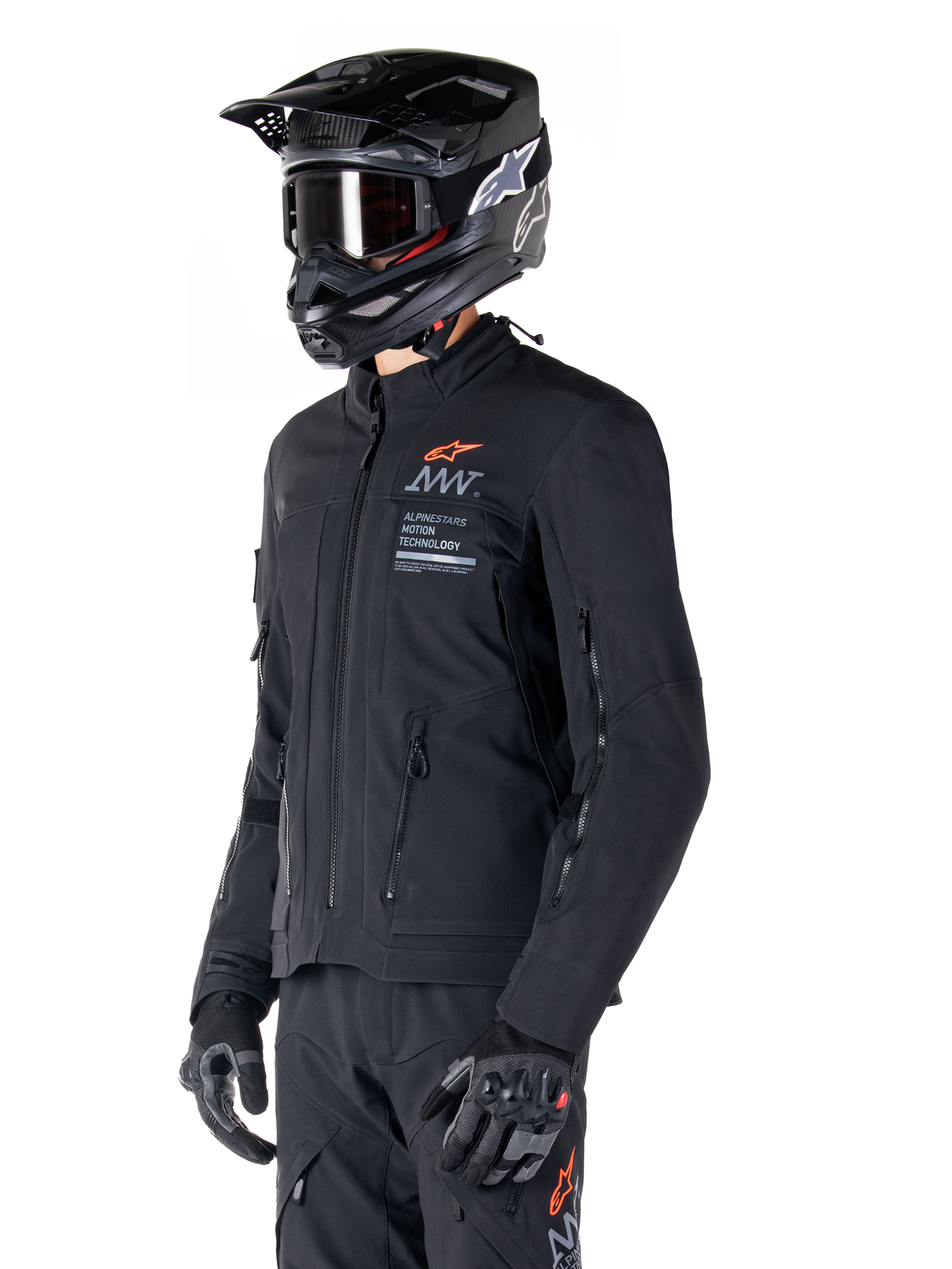 Giacca Alpinestars AMT-8 Stretch Drystar® XF, nera, indossata da un pilota con pantaloni e guanti adventure abbinati, completa di casco da motocross nero e occhiali, aperture di ventilazione con cerniera su petto e braccia, marchio Alpinestars Motion Technology con logo arancione, abbigliamento adventure-touring premium
