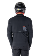 Giacca Alpinestars AMT-8 Stretch Drystar® XF, vista posteriore, nera, indossata con casco e pantaloni neri, con marchio Alpinestars Motion Technology sul retro, design adventure touring in materiale elasticizzato ergonomico.