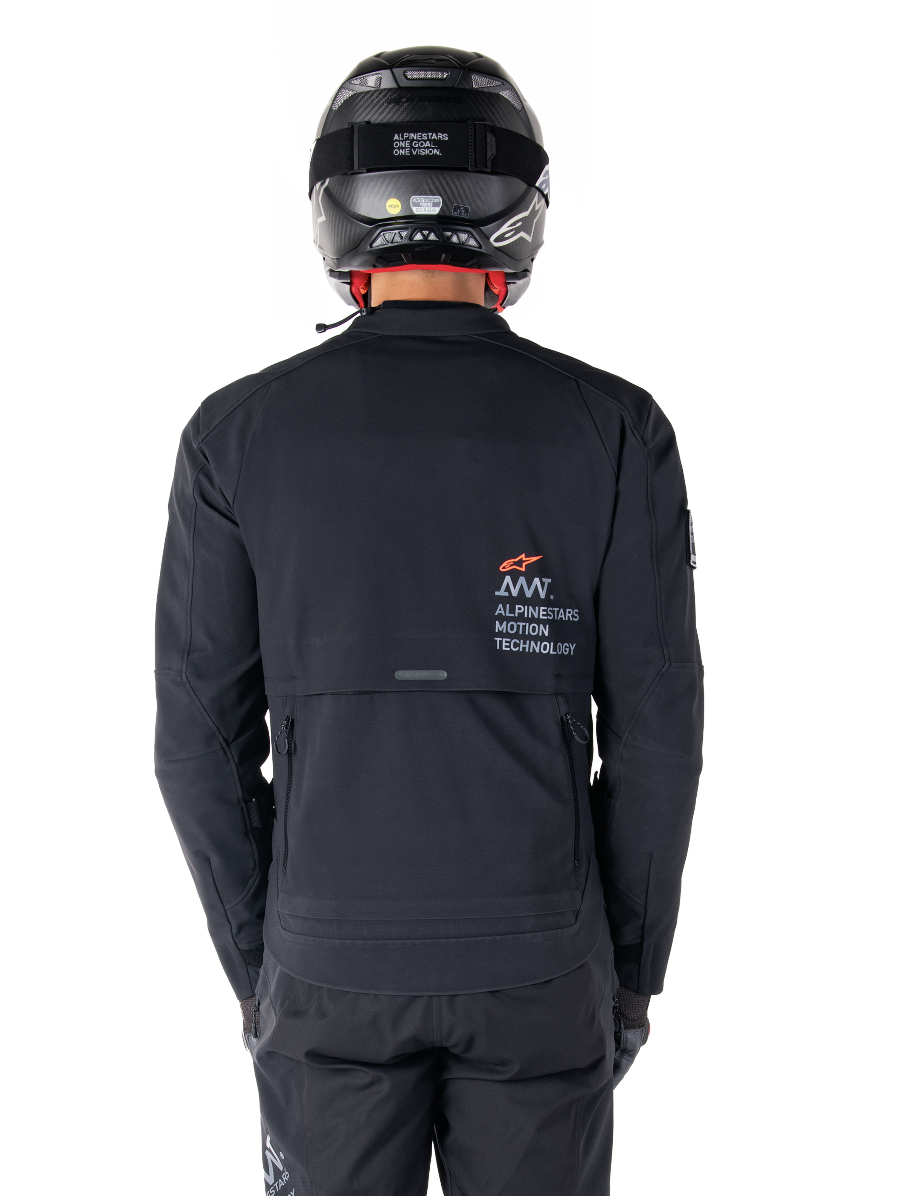 Giacca Alpinestars AMT-8 Stretch Drystar® XF, vista posteriore, nera, indossata con casco e pantaloni neri, con marchio Alpinestars Motion Technology sul retro, design adventure touring in materiale elasticizzato ergonomico.