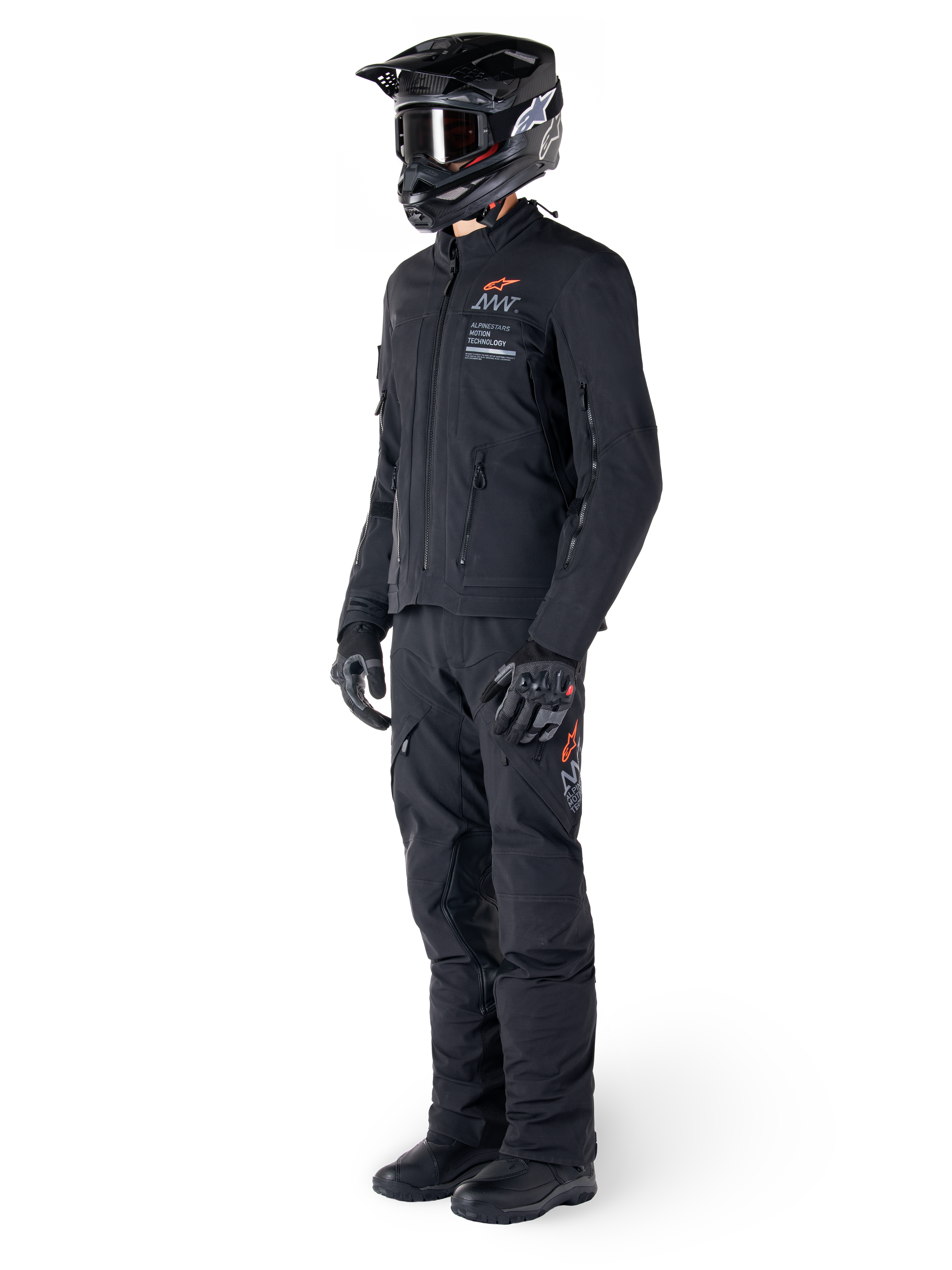 Alpinestars AMT-8 Stretch Drystar® XF Jacket, giacca da moto adventure, nero, indossata con pantaloni coordinati, casco e guanti, con marchio Alpinestars Motion Technology e accenti arancioni, struttura elasticizzata resistente per la guida adventure