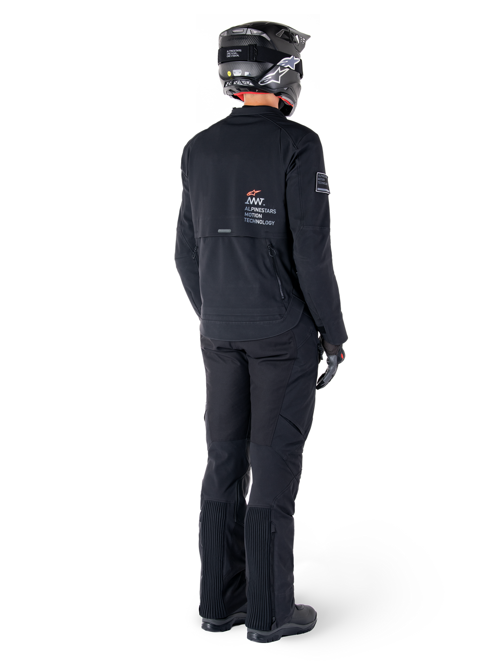 Giacca Alpinestars AMT-8 Stretch Drystar® XF, nera, vista posteriore di un pilota che indossa la giacca con pantaloni neri coordinati e un casco nero, con il marchio 'Alpinestars Motion Technology' sulla schiena, materiale tecnico elasticizzato per la guida adventure in moto