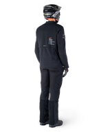 Giacca Alpinestars AMT-8 Stretch Drystar® XF, nera, vista posteriore di un pilota che indossa la giacca con pantaloni neri coordinati e un casco nero, con il marchio 'Alpinestars Motion Technology' sulla schiena, materiale tecnico elasticizzato per la guida adventure in moto