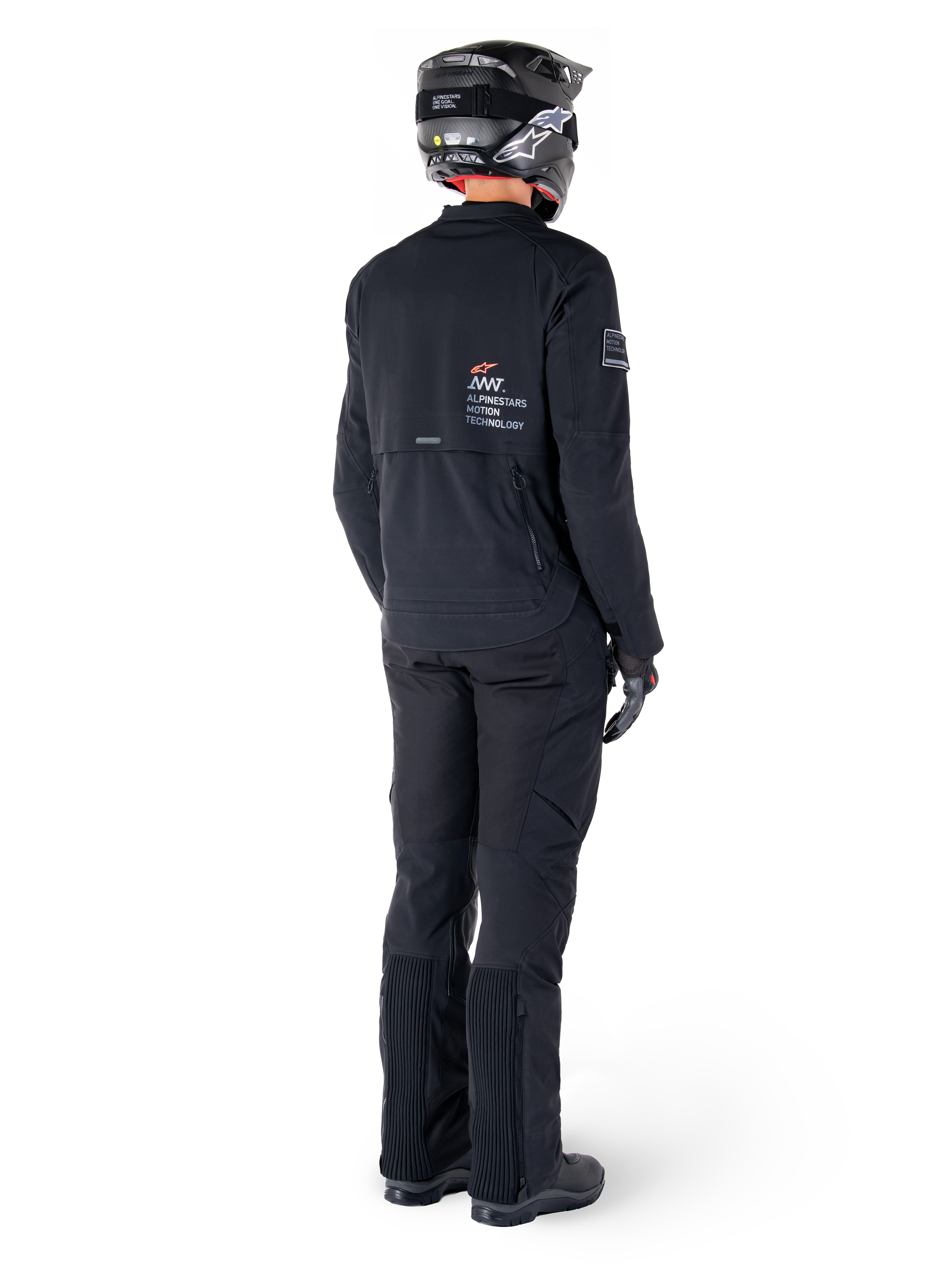 Giacca Alpinestars AMT-8 Stretch Drystar® XF, nera, vista posteriore di un pilota che indossa la giacca con pantaloni neri coordinati e un casco nero, con il marchio 'Alpinestars Motion Technology' sulla schiena, materiale tecnico elasticizzato per la guida adventure in moto