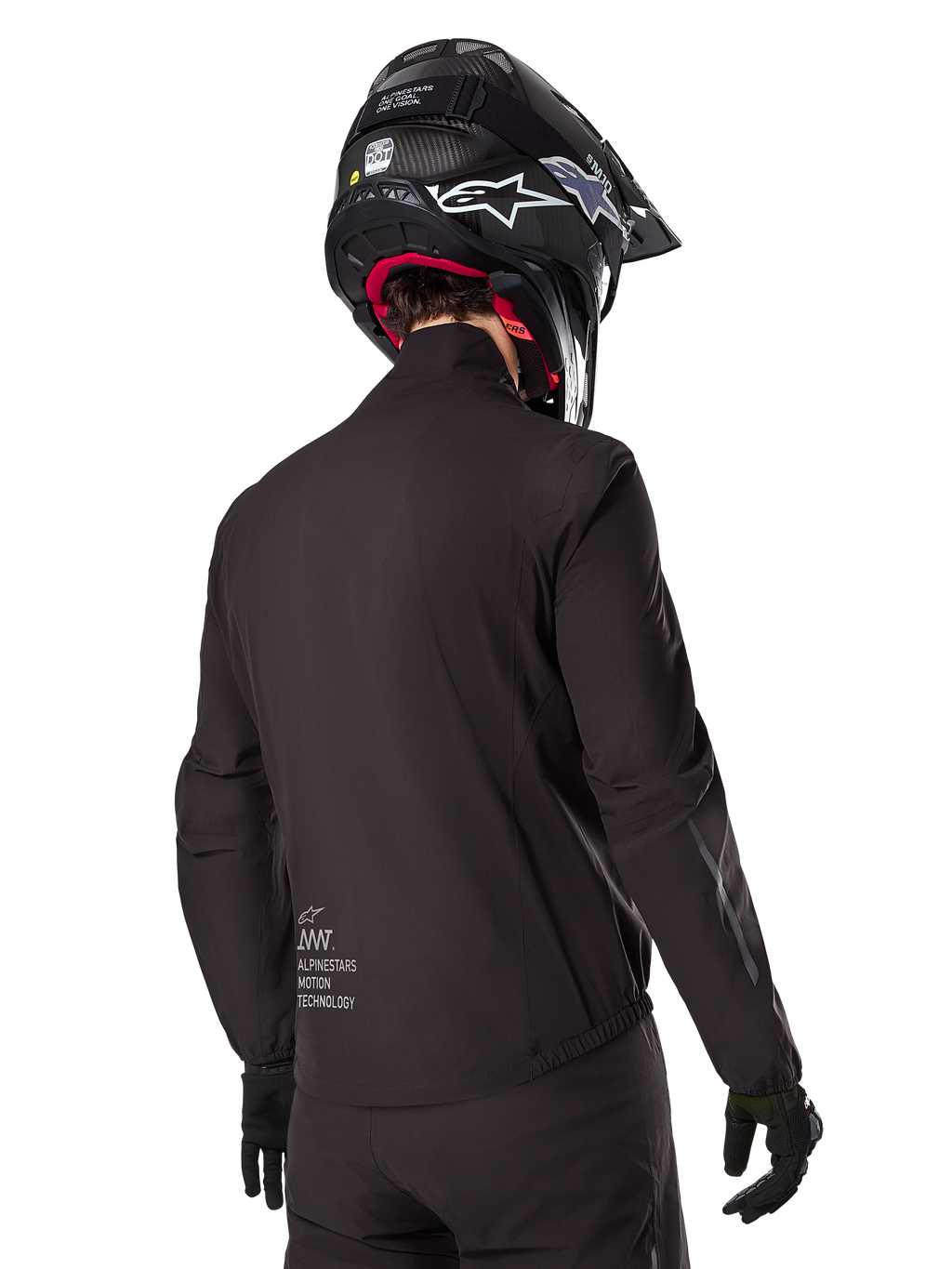 Alpinestars AMT-8 Stretch Drystar® XF Liner, fodera per giacca impermeabile nera, vista posteriore di un pilota che indossa un casco e guanti neri, logo Alpinestars Motion Technology sulla parte bassa della schiena, design minimalista e funzionale per la guida adventure