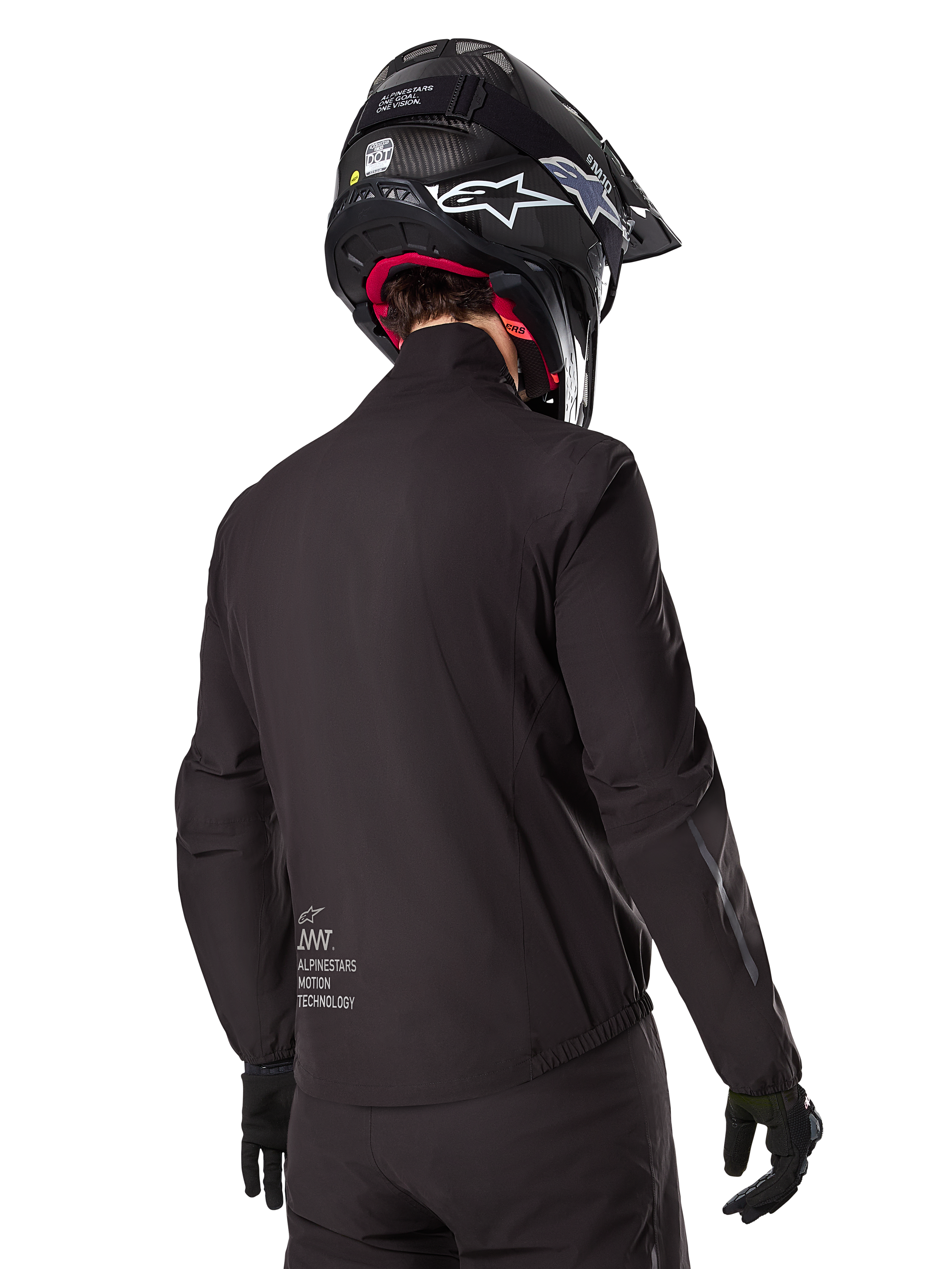 Alpinestars AMT-8 Stretch Drystar® XF Liner, fodera per giacca impermeabile nera, vista posteriore di un pilota che indossa un casco e guanti neri, logo Alpinestars Motion Technology sulla parte bassa della schiena, design minimalista e funzionale per la guida adventure