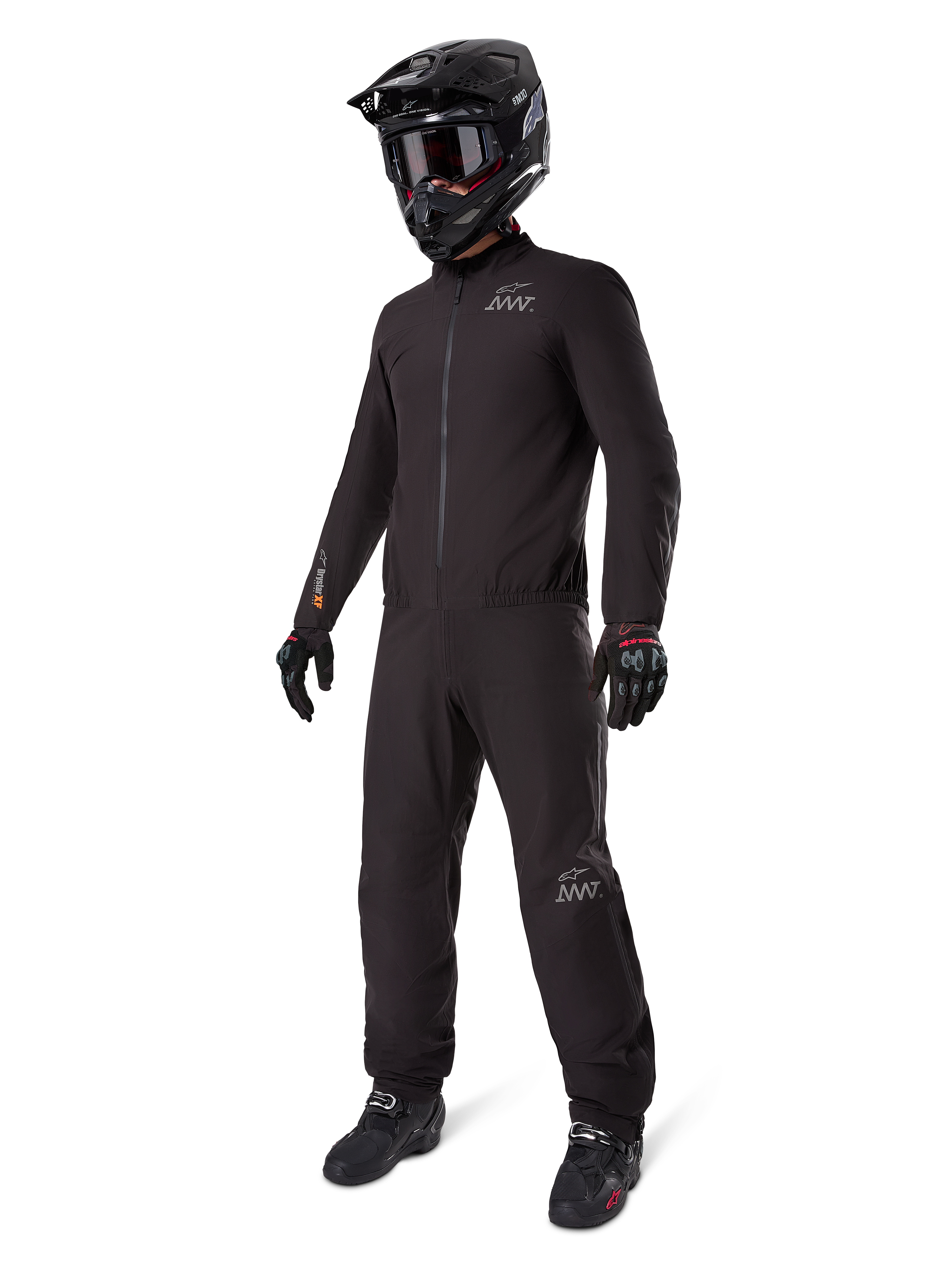 Alpinestars AMT-8 Stretch Drystar® XF Liner, completo da moto impermeabile nero, indossato con casco, occhiali e guanti neri, con loghi AMT e Drystar XF, abbigliamento adventure funzionale per protezione in ogni condizione climatica.