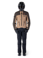 Giacca Alpinestars AMT-8 Stretch Drystar® XF, giacca da moto adventure, marrone scuro e dark khaki, indossata con casco nero, occhiali, guanti neri, pantaloni neri e stivali neri, con prese d'aria sul petto e marchio AMT, equipaggiamento coordinato per adventure touring
