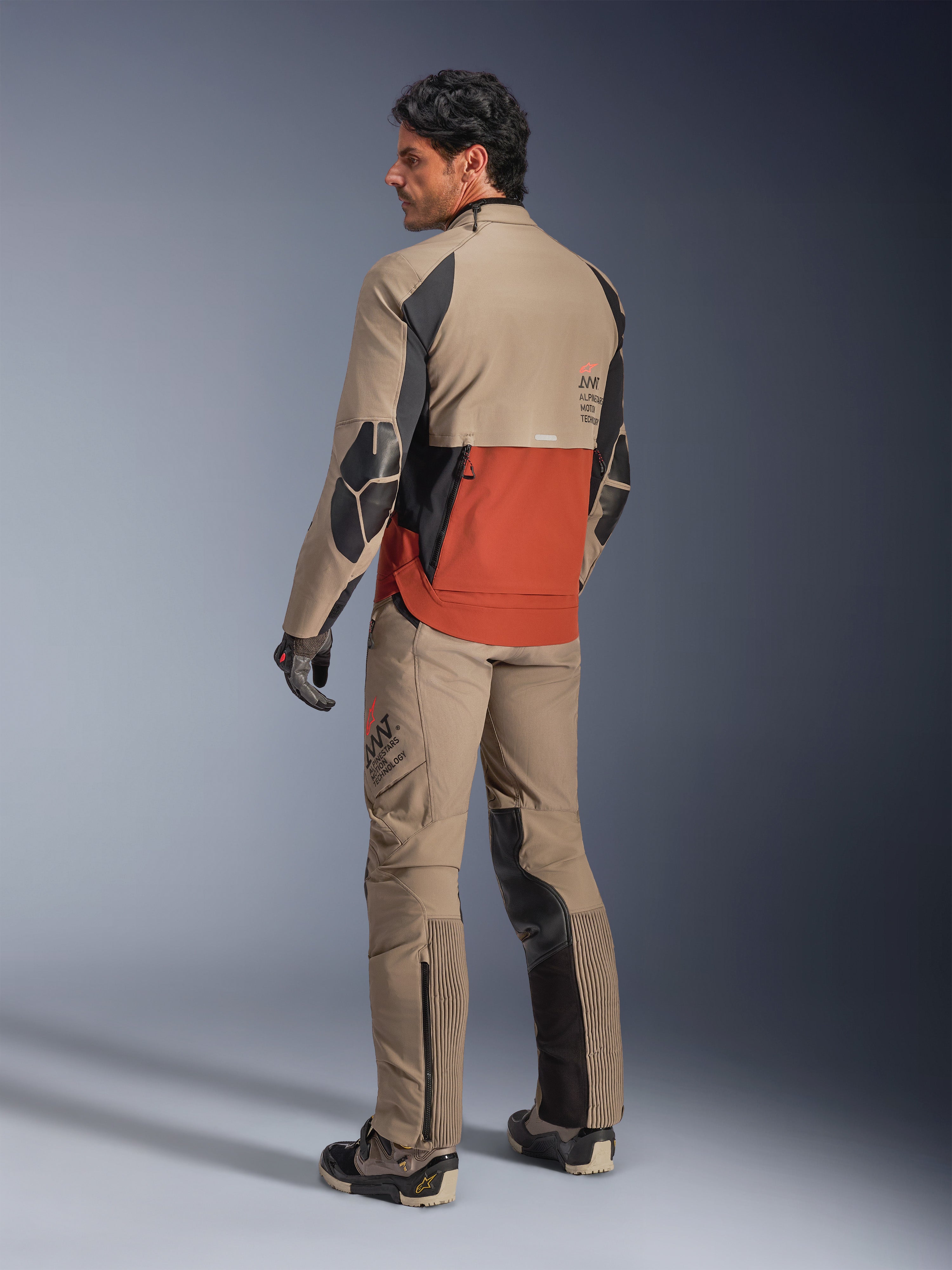 Giacca Alpinestars AMT-8 Stretch Drystar® XF, giacca da moto adventure, Walnut Rust e nero, vista posteriore su modello indossata con pantaloni adventure e stivali coordinati, abbigliamento in tessuto altamente traspirante per touring