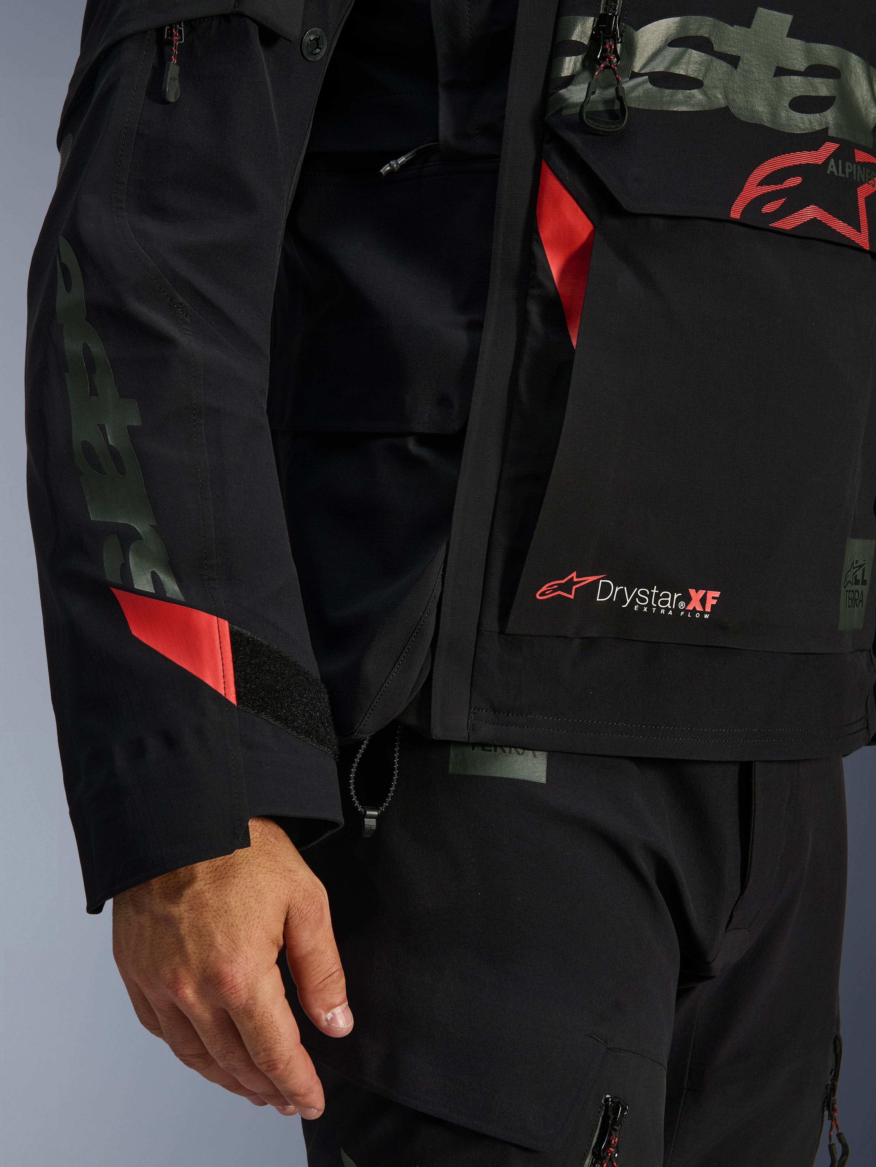 Alpinestars Halo Pro Drystar® XF Laminated Jacket, giacca da moto, nera con accenti rossi, primo piano con marchio Drystar® XF, texture tecnica del guscio laminato e dettagli regolabili sulle maniche per guida adventure