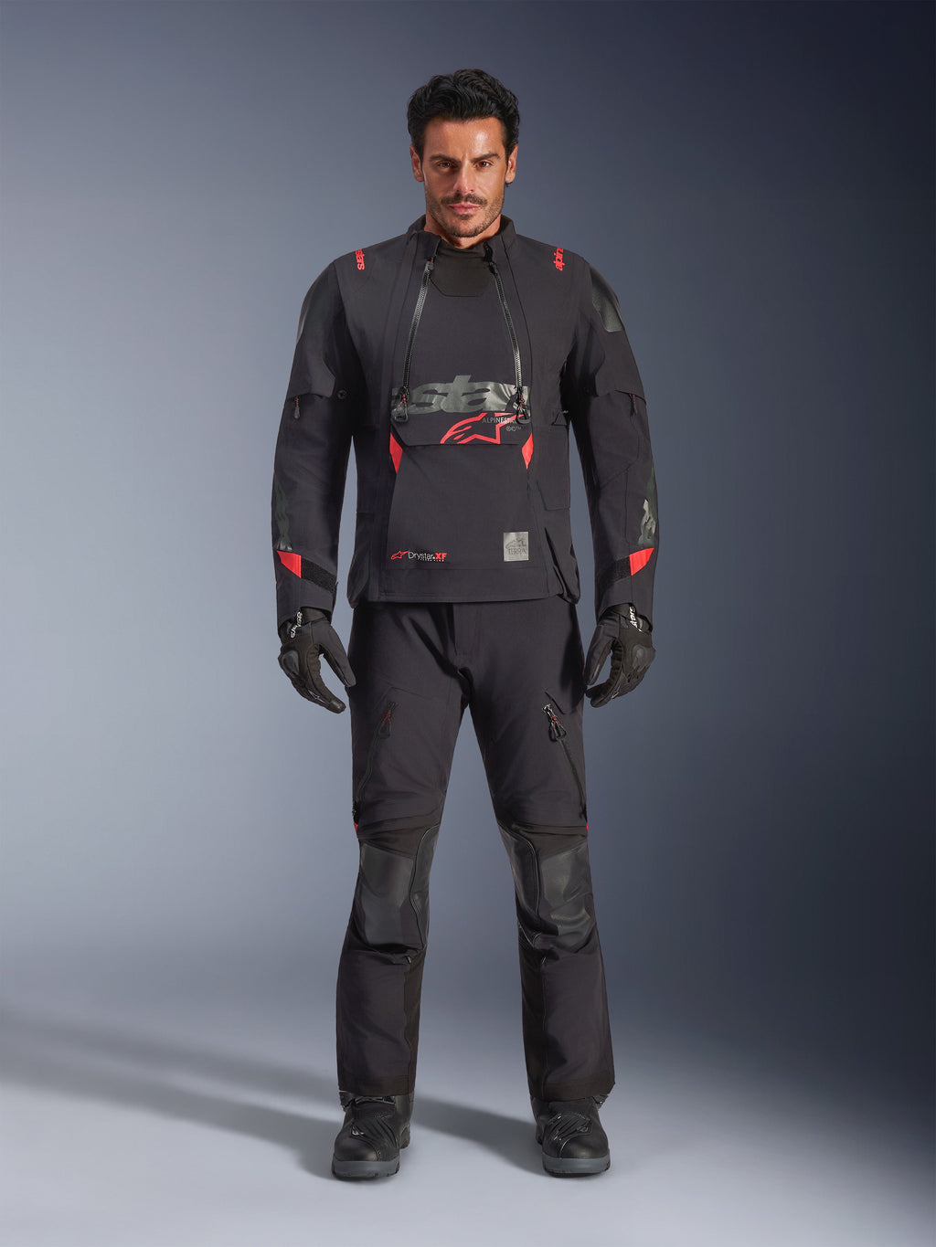 Giacca Alpinestars Halo Pro Drystar® XF Laminated, colore Black Dark Shadow con accenti rossi, set completo da moto adventure con pantaloni e guanti coordinati, design modulare in tessuto con pannelli di ventilazione anteriori e logo evidente sul petto.