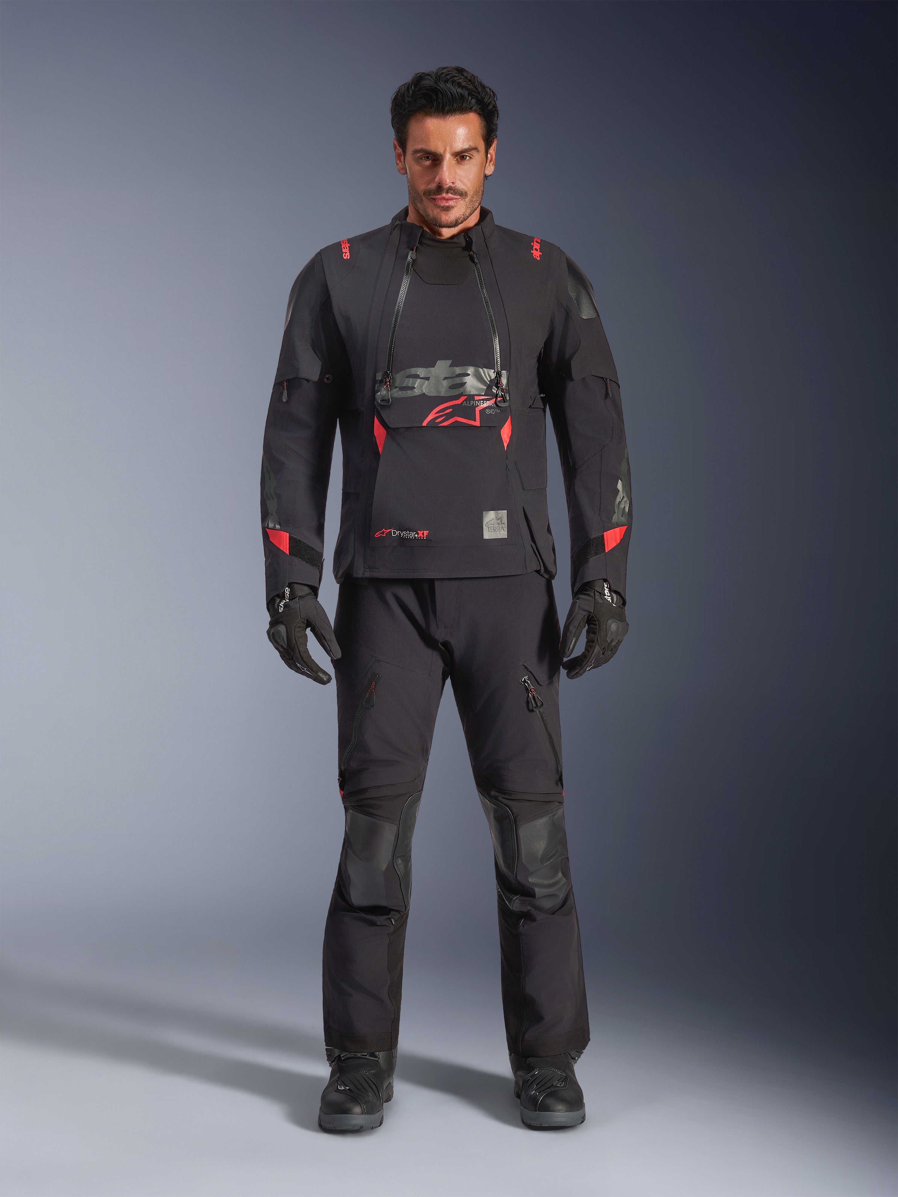 Giacca Alpinestars Halo Pro Drystar® XF Laminated, colore Black Dark Shadow con accenti rossi, set completo da moto adventure con pantaloni e guanti coordinati, design modulare in tessuto con pannelli di ventilazione anteriori e logo evidente sul petto.