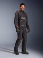 Motociclista con giacca Alpinestars Halo Pro Drystar® XF Laminated in Black Dark Shadow, abbigliamento adventure completo con pantaloni, guanti e stivali coordinati, pannelli frontali asimmetrici modulari e accenti rossi del marchio