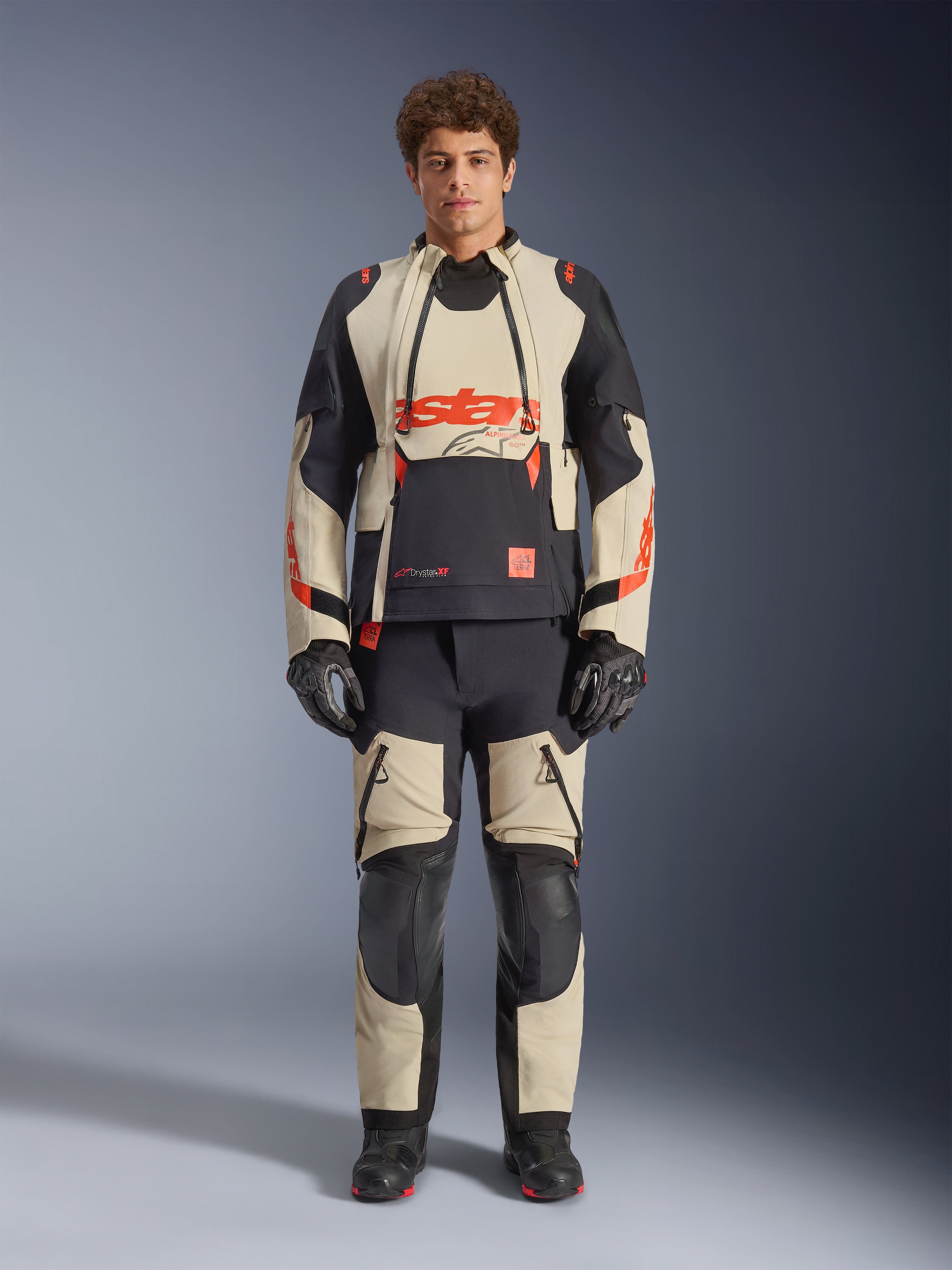 Alpinestars Halo Pro Drystar® XF Laminated Jacket, Mastic Black, giacca da moto adventure indossata da un modello con pantaloni e guanti coordinati, pannelli in tessuto mastice e nero con loghi rossi audaci, design modulare per la guida su ogni terreno