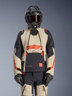 Alpinestars Halo Pro Drystar XF Laminated Jacket, giacca da moto adventure in Mastic Black e beige con accenti rossi, indossata con equipaggiamento protettivo completo inclusi casco e guanti, dotata di pannelli di ventilazione modulari e costruzione laminata 3L.