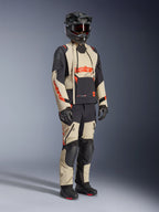 Alpinestars Halo Pro Drystar® XF Laminated Jacket in Mastic Black, giacca da moto adventure indossata con pantaloni coordinati, casco integrale, guanti e stivali, caratterizzata da pannelli beige e neri con loghi rossi, design tecnico multistagione.