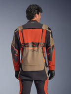 Giacca laminata Alpinestars Halo Pro Drystar® XF, colorazione Walnut Rust Black, vista posteriore, con ampio pannello posteriore arancione, marchio ASTARS nero, tasca portaoggetti inferiore walnut e colletto Tech-Air® Ready, indossata con pantaloni adventure coordinati e guanti neri