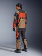 Giacca laminata Alpinestars Halo Pro Drystar® XF, giacca da moto adventure Walnut Rust Black, vista posteriore indossata con pantaloni coordinati e stivali neri, caratterizzata da materiale tecnico stretch 3L, pannelli di ventilazione modulari e branding arancione sul retro.