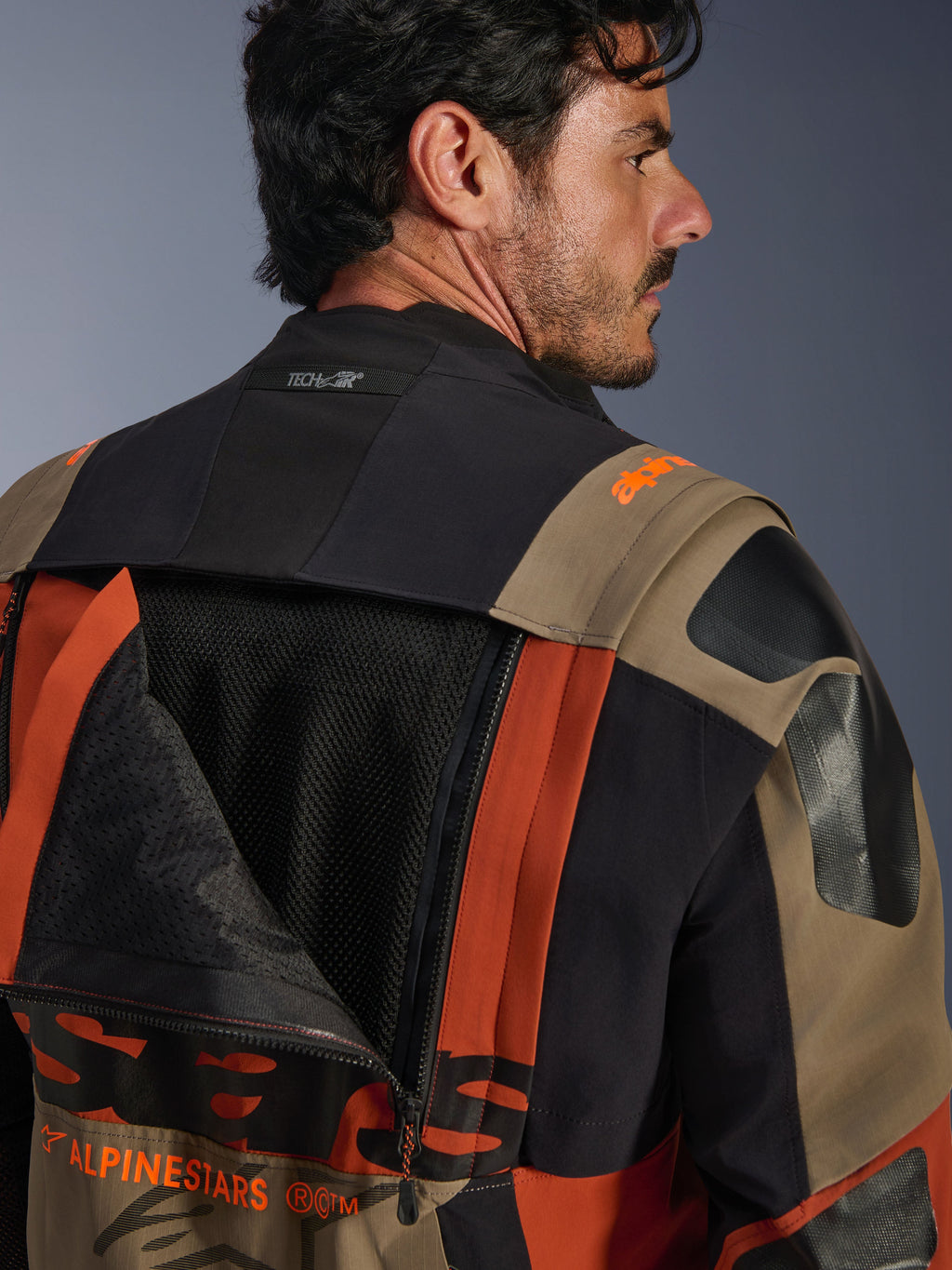 Giacca laminata Alpinestars Halo Pro Drystar® XF in Walnut Rust Black, vista posteriore ravvicinata con pannello di ventilazione aperto che mostra la rete interna, logo Tech-Air® sul colletto e robusta costruzione in tessuto multicolore.