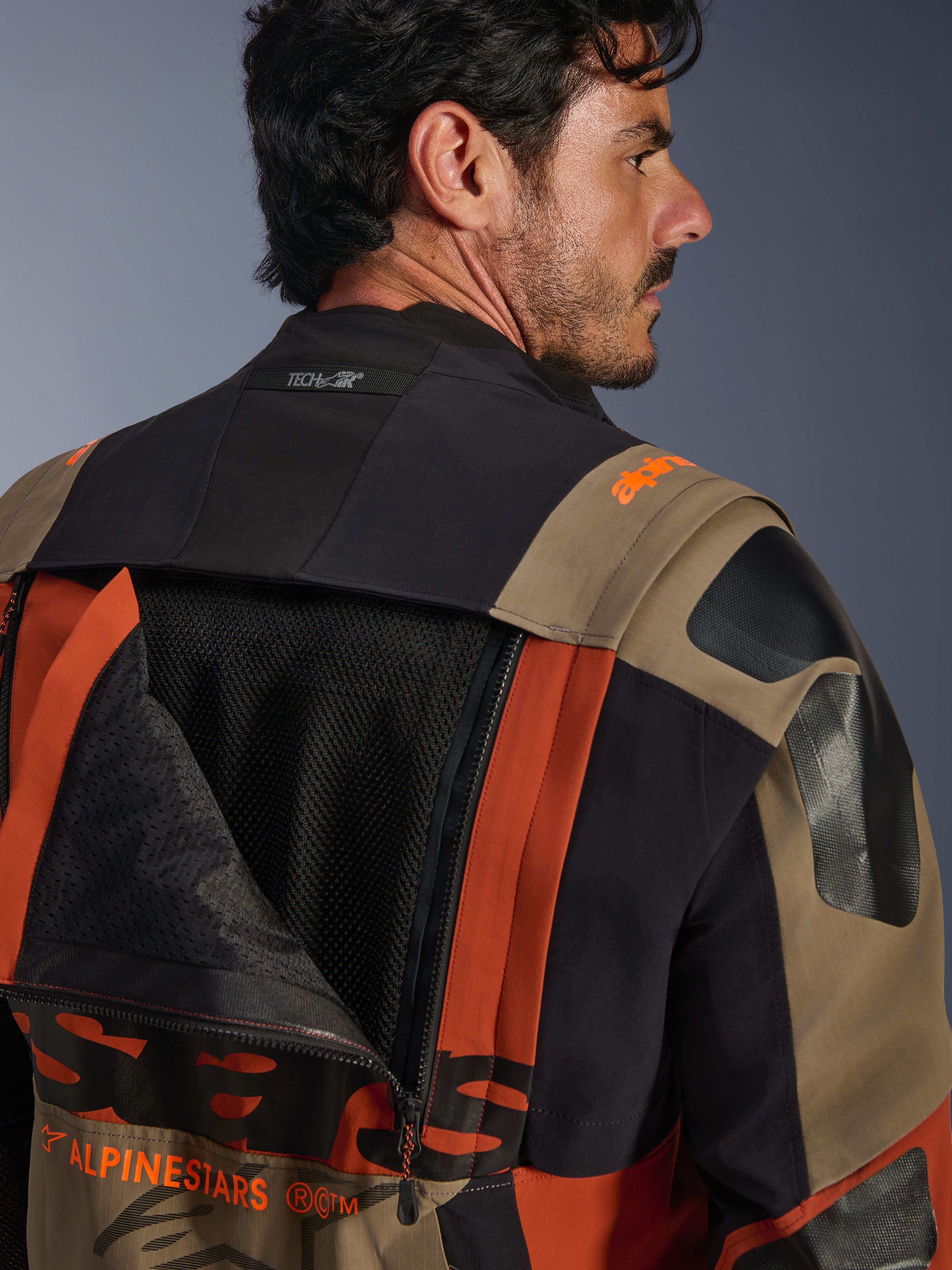 Giacca laminata Alpinestars Halo Pro Drystar® XF in Walnut Rust Black, vista posteriore ravvicinata con pannello di ventilazione aperto che mostra la rete interna, logo Tech-Air® sul colletto e robusta costruzione in tessuto multicolore.