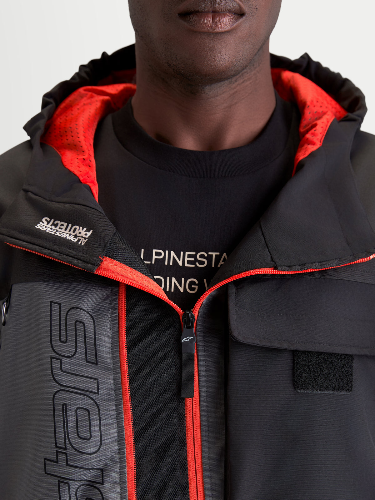 Alpinestars Morfex Parka Wp Giacca, giacca da moto urbana contemporanea da uomo, grigio lunare e nero, vista in primo piano con cappuccio integrato, fodera interna rossa e dettagli delle tasche sul petto indossata da un modello