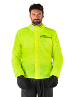 Alpinestars Hurricane Rain V2 Jacket, giacca antipioggia da moto, giallo fluo, indossata da un modello con pantaloni e guanti neri, colletto alto con linguette riflettenti, patta protettiva anteriore con logo Alpinestars, abbigliamento impermeabile ad alta visibilità