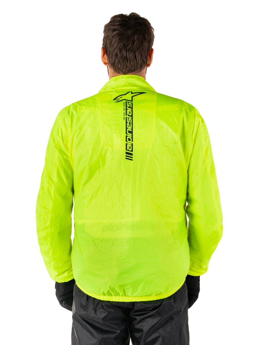 Giacca Alpinestars Hurricane Rain V2, giacca antipioggia da moto, giallo fluo, vista posteriore con logo Alpinestars nero verticale al centro della schiena, tessuto impermeabile leggero, indossata con pantaloni e guanti da moto neri