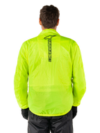 Giacca Alpinestars Hurricane Rain V2, giacca antipioggia da moto, giallo fluo, vista posteriore con logo Alpinestars nero verticale al centro della schiena, tessuto impermeabile leggero, indossata con pantaloni e guanti da moto neri