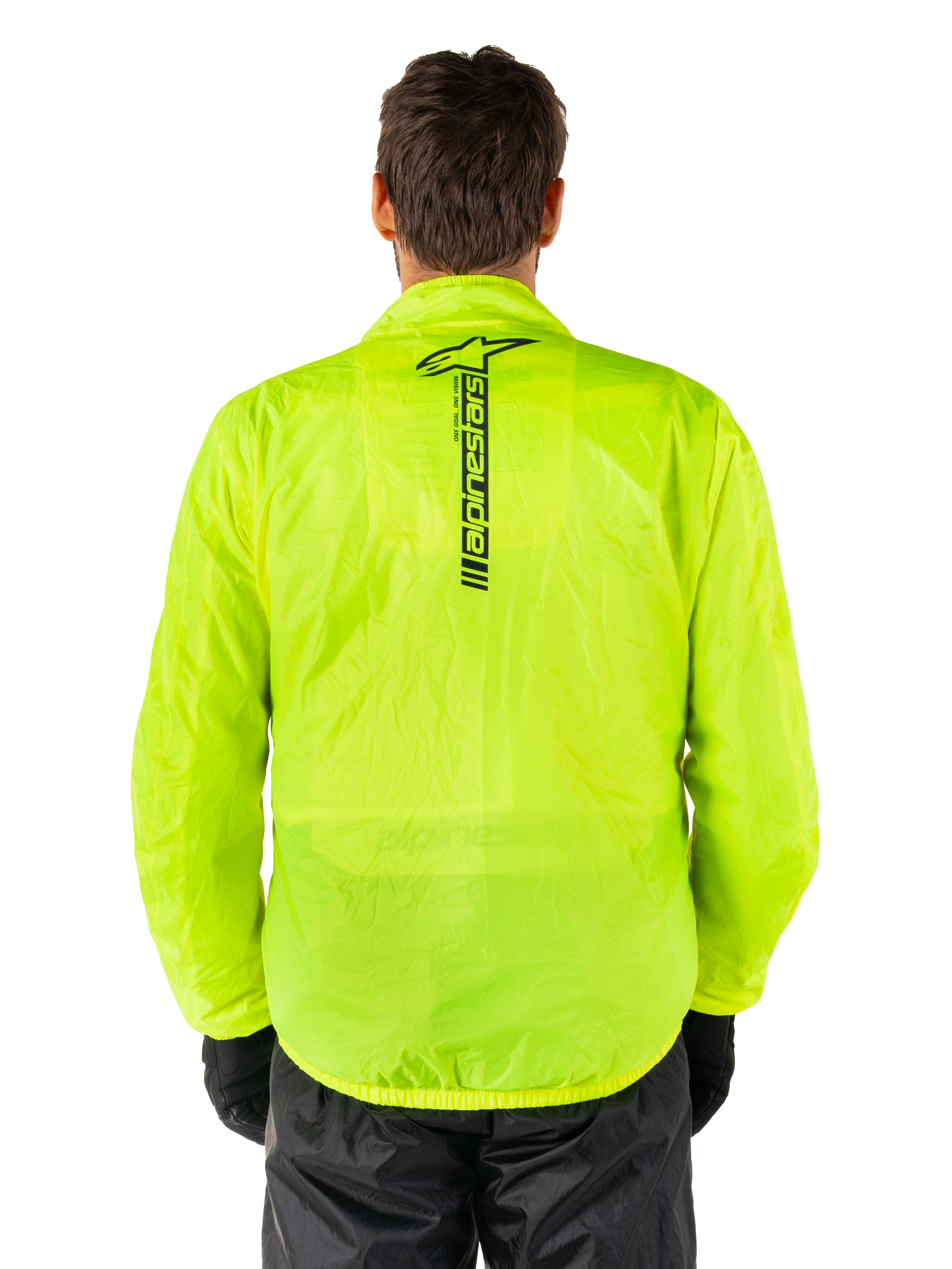 Giacca Alpinestars Hurricane Rain V2, giacca antipioggia da moto, giallo fluo, vista posteriore con logo Alpinestars nero verticale al centro della schiena, tessuto impermeabile leggero, indossata con pantaloni e guanti da moto neri