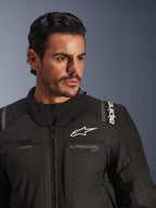 Giacca Alpinestars Andes V4 Drystar®, nero, indossata da un modello, primo piano su petto e spalle, con loghi Alpinestars bianchi, materiale tessile con dettagli di ventilazione e asola per tubo di idratazione, abbigliamento da moto adventure-touring