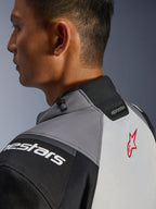 Giacca Alpinestars Andes V4 Drystar®, primo piano del colletto e della parte superiore della schiena, grigio scuro e grigio ghiaccio con accenti neri, logo a stella rosso, con regolatore a cordoncino sul colletto e marchio Alpinestars, struttura in tessuto resistente