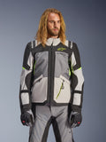 Giacca Alpinestars Andes V4 Drystar, giacca da moto adventure touring, grigio scuro e grigio ghiaccio con dettagli giallo neon, indossata da un modello con pantaloni e guanti coordinati, design multitasca in tessuto per la guida in ogni condizione atmosferica