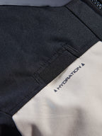 Giacca Alpinestars Andes V4 Drystar®, dettaglio ravvicinato del passante per il tubo di idratazione sul petto, colorazione Walnut Mastic e nero, tessuto tessile resistente con etichetta stampata 'HYDRATION', caratteristica pratica per la guida di moto adventure