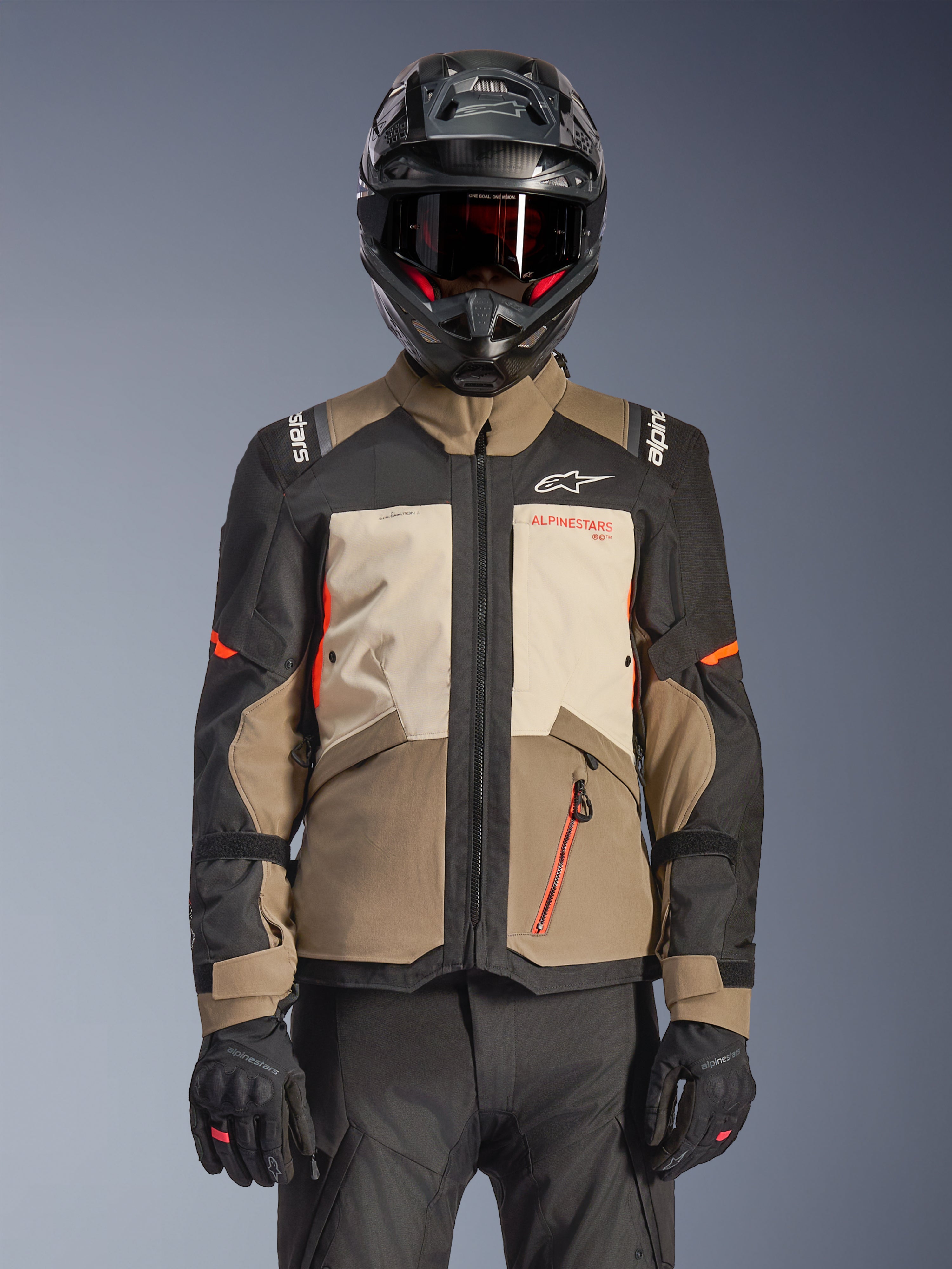 Giacca Alpinestars Andes V4 Drystar®, Walnut Mastic Black, giacca da adventure touring con pannelli marrone noce e crema mastice, maniche nere e accenti arancione vivace, indossata con casco da moto nero, occhiali scuri e guanti neri