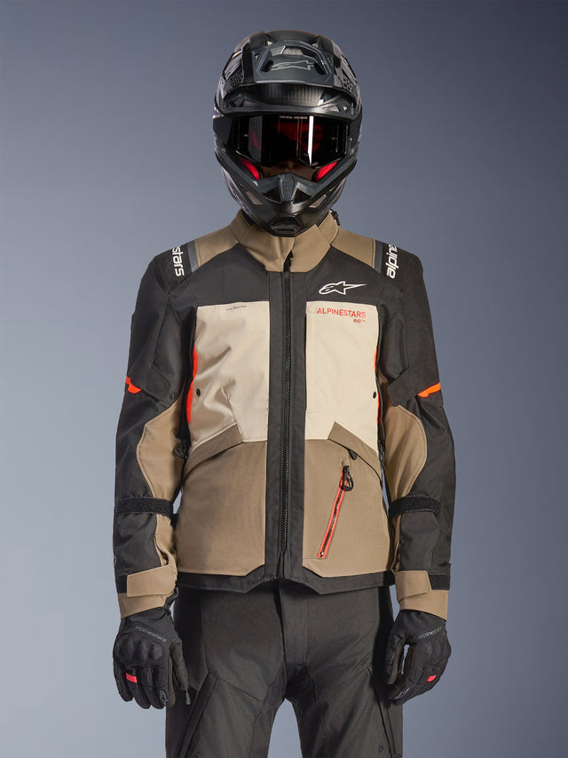 Giacca Alpinestars Andes V4 Drystar®, Walnut Mastic Black, giacca da adventure touring con pannelli marrone noce e crema mastice, maniche nere e accenti arancione vivace, indossata con casco da moto nero, occhiali scuri e guanti neri