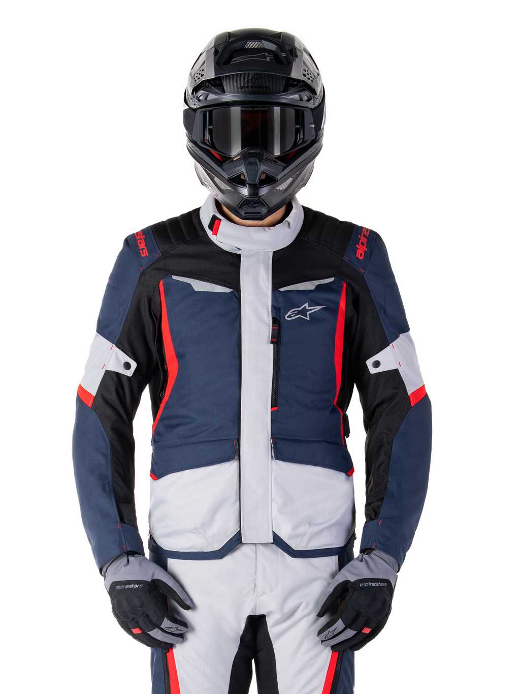 Giacca Alpinestars ST-1 Waterproof, giacca da adventure touring, blu scuro, nero e rosso brillante, indossata con casco adventure nero e guanti grigi, pannelli grigio chiaro e accenti rossi su spalle e cerniere, design elegante con logo Alpinestars sul petto, abbigliamento impermeabile resistente per la guida in moto